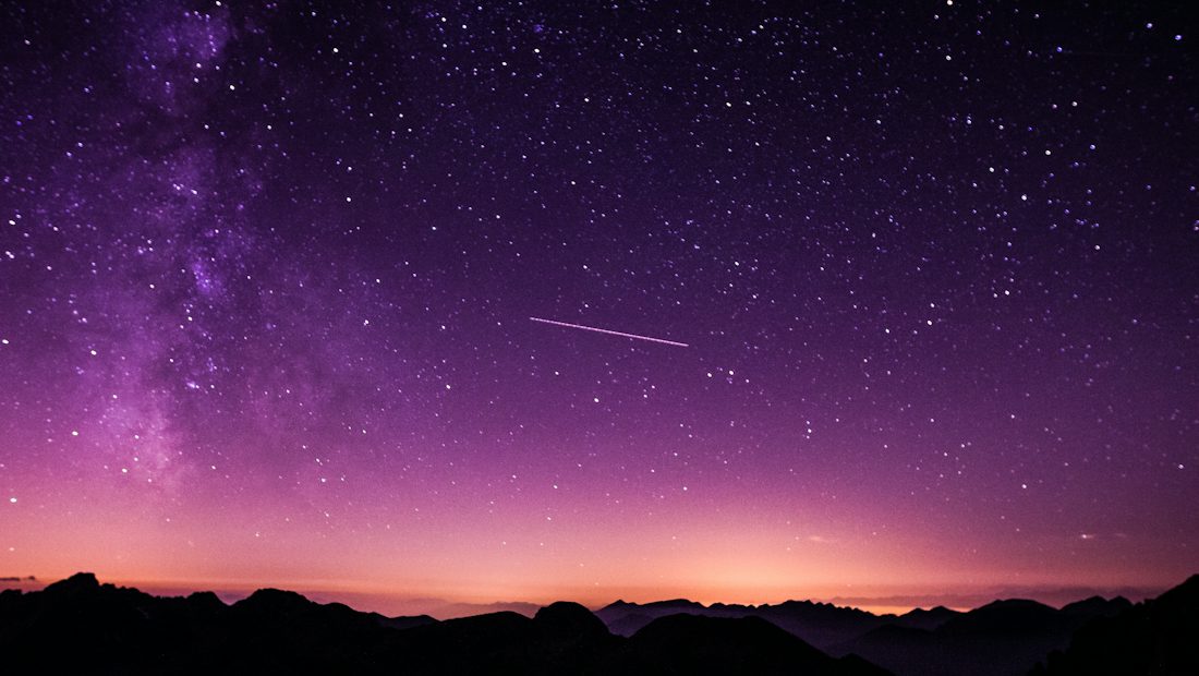 A shooting star crossing a night sky full of stars