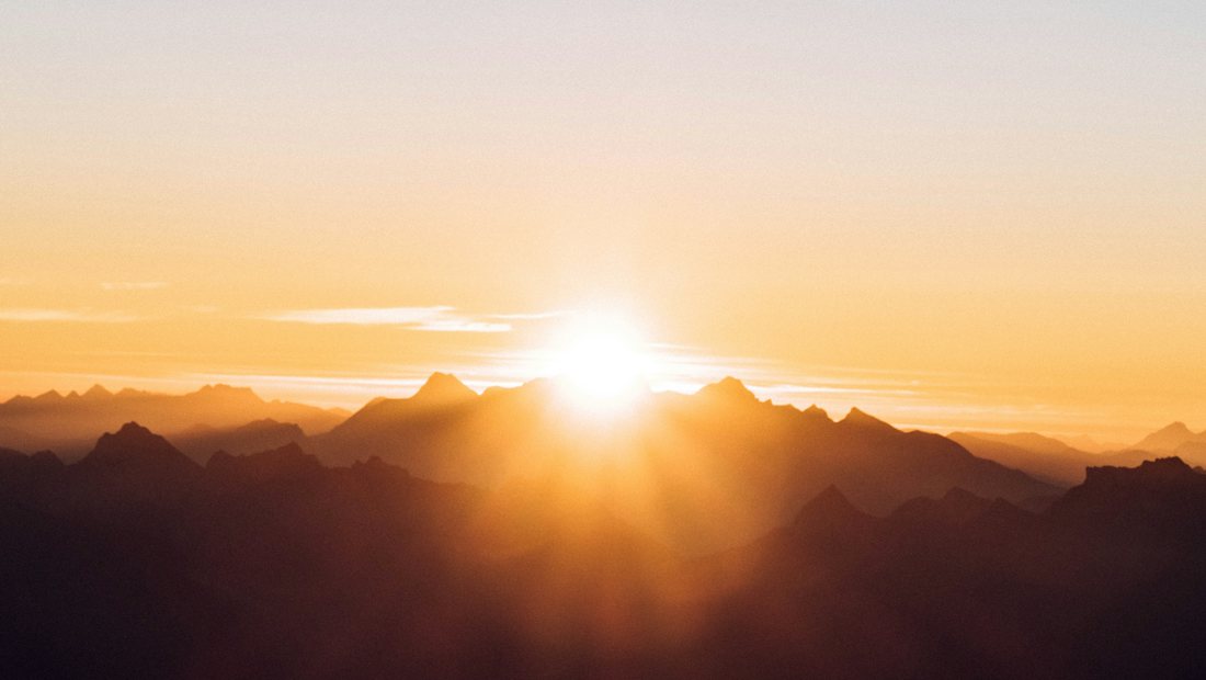 The sun rising over a line of mountains